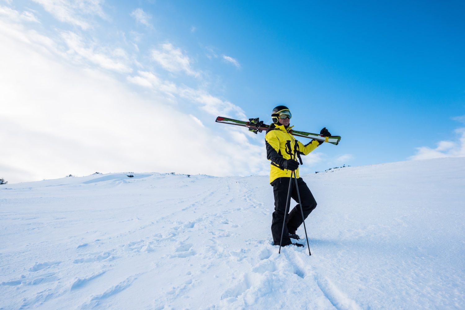 sportsman in helmet standing with ski sticks on snow in mountains